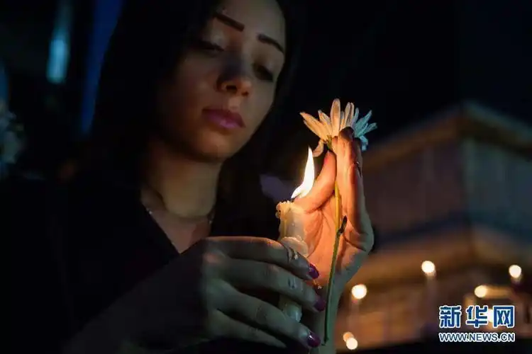 5月24日,在埃及首都开罗记协大楼前,一名女子手捧蜡烛和白花参加烛光