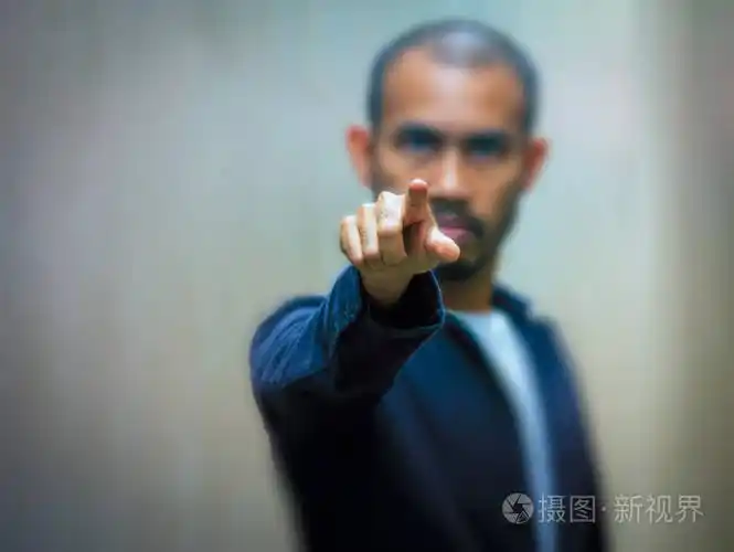 一个穿着蓝色衬衫的亚洲人用愤怒的表情指着他的手指.有选择的焦点.