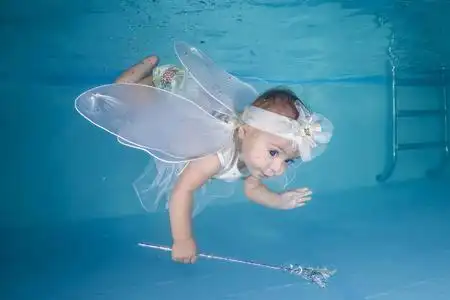 穿着仙女服装的小女孩在游泳池里潜入水中照片