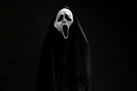 有人在黑色封面与白色幽灵面具角色扮演魔鬼表演爬可怕的 gost 在黑色