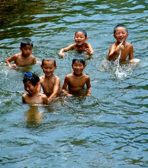 村前缓缓淌过一条小溪,孩子们在戏水,那水溅起朵朵浪花,孩子们露出