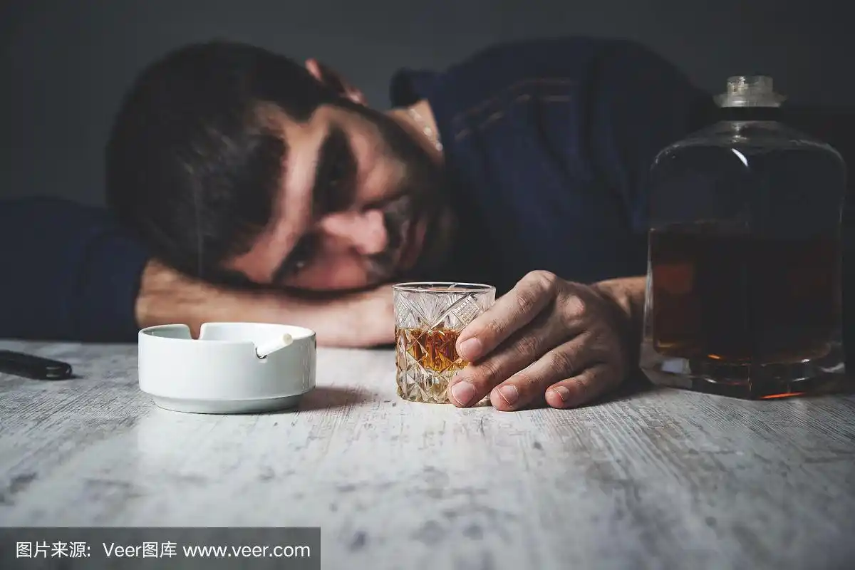 悲伤的男人手里拿着威士忌和香烟