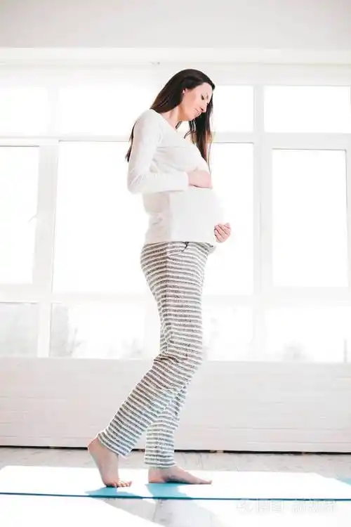 怀孕的女人在家里行走和抱腹