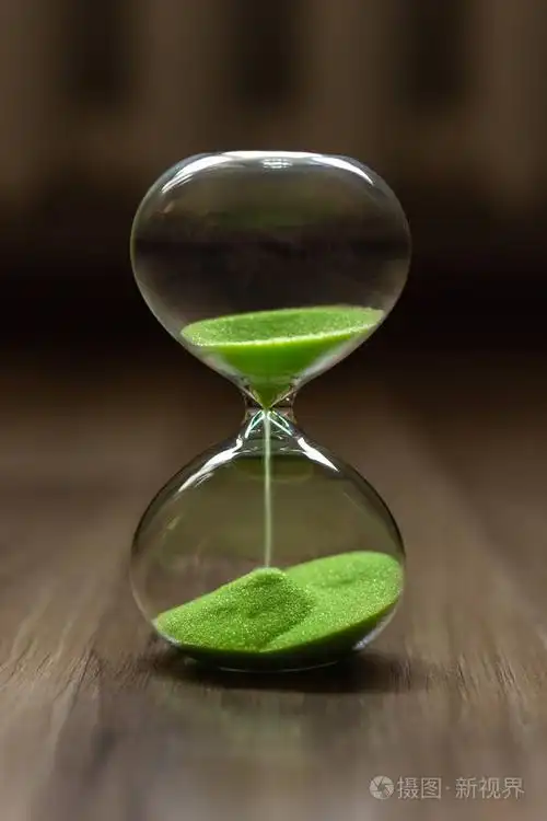 沙漏与绿色沙子在一个模糊的背景