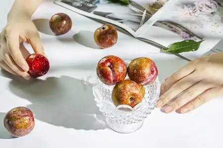 三华李水果下午茶下午三华李室内手拿摄影图配图