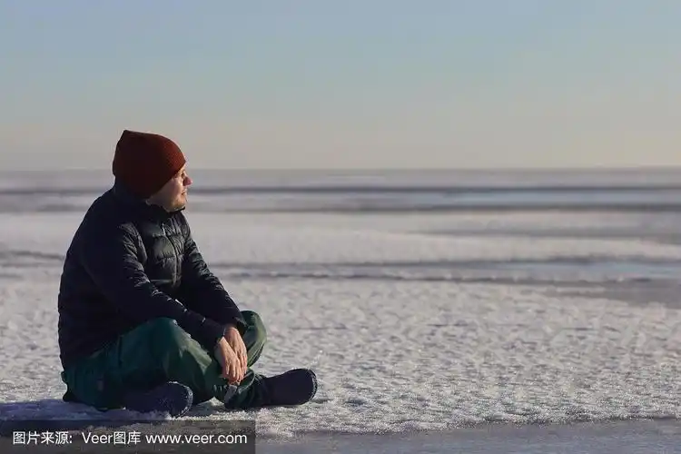 冬天,一个年轻人坐在冰天雪地上看着太阳.