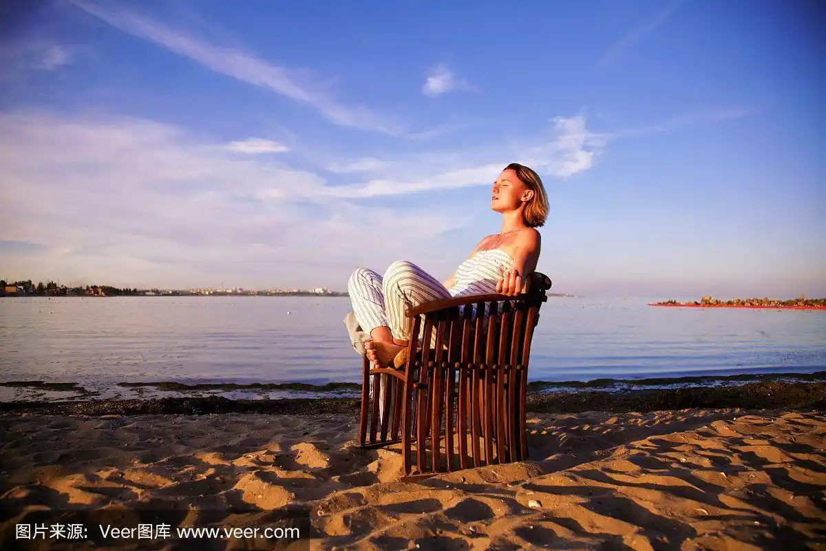 年轻漂亮的女人在海滩上晒太阳