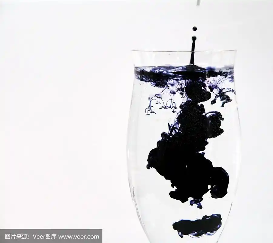 蓝色和黑色的墨水滴进酒杯里的水