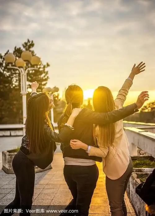 三个快乐的朋友在户外的人行道上欣赏日落