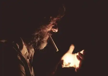 黑暗中点烟的男子