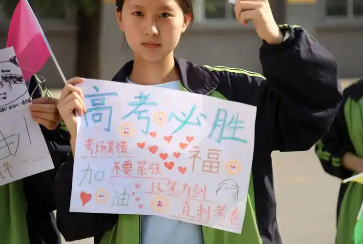 一名手拿麦克风的同学,高高举着"加油,高考必胜"的宣传牌,带着大家一