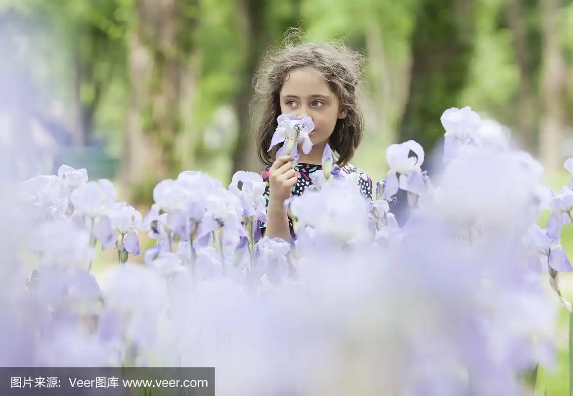 一个小女孩在公园里闻花的肖像