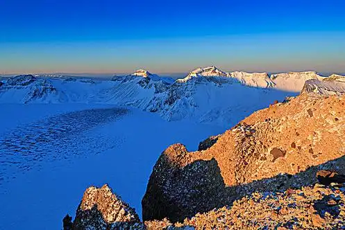 暖光下的长白山天池熔岩