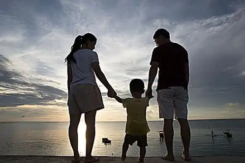 一家人树林里手牵手站着的三口之家的后视图坐在扫把上出行的一家三口