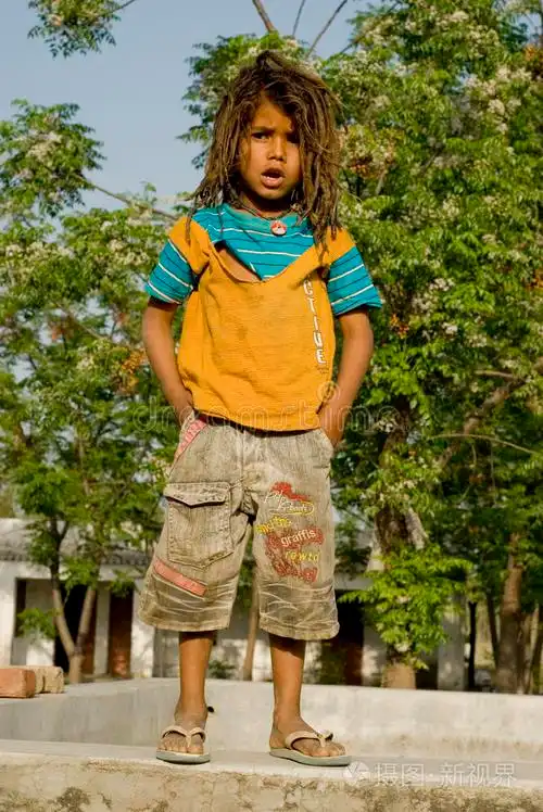 一个穿拖鞋的男孩站在小墙上