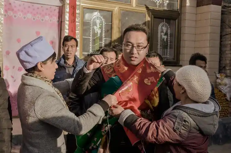 亲戚给新郎李剑文佩挂红绸被面,新郎像中状元一样,红利红火,喜气洋洋.