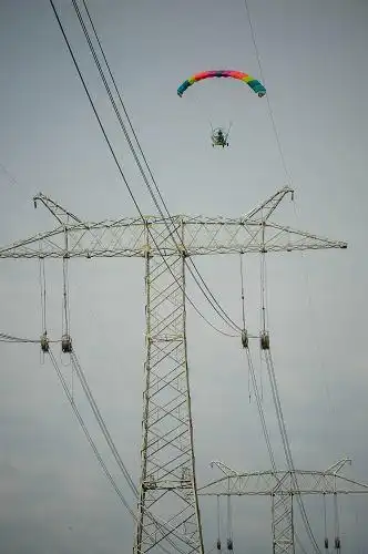 8月15日,动力伞飞行在已经建好的输电铁塔上进行高空架线