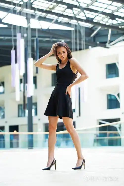 一个穿着黑色衣服的快乐的年轻黑发女人的全身肖像照片-正版商用图片