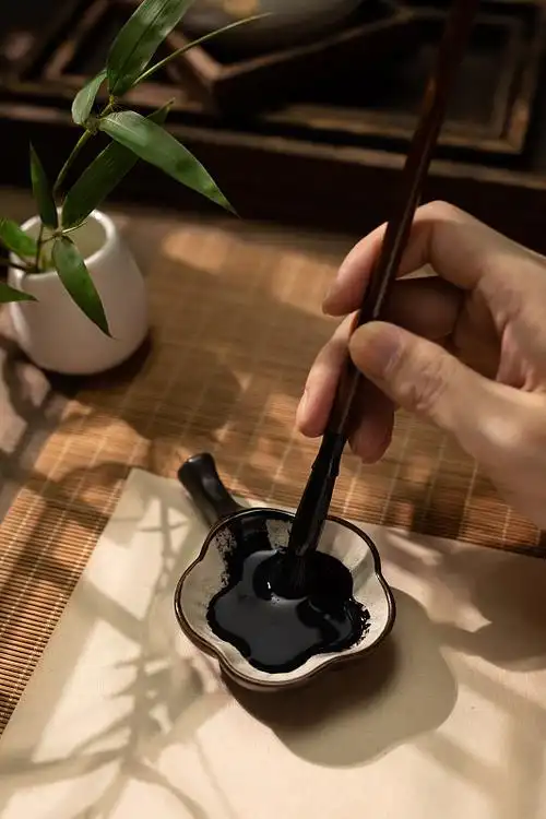 手拿毛笔蘸墨水特写图片下载