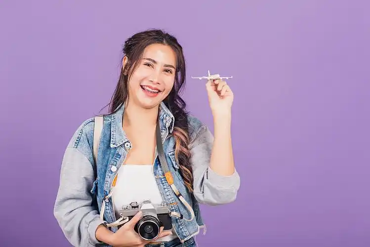 女人兴奋地微笑着拿着飞机玩具和复古相机图片下载
