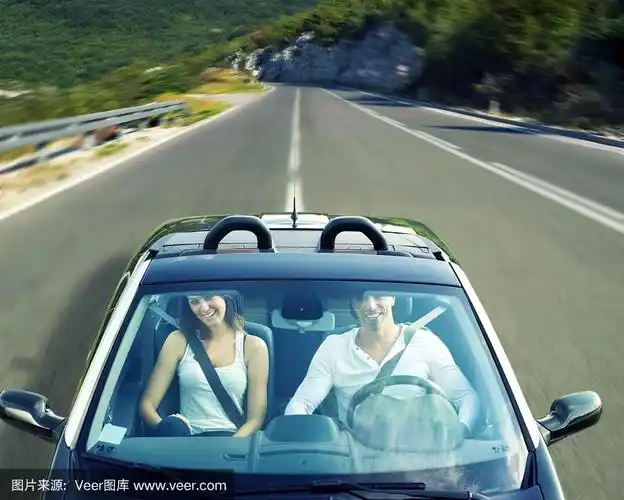 一对年轻夫妇开着一辆敞篷车在路上兜风
