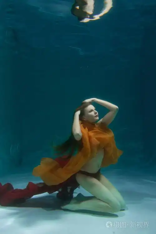 美丽的白种人长发女人独自穿着红色性感内衣在水下游泳