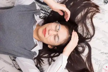 亚洲的男婴躺在哭泣眼镜女人躺在床上放松照片