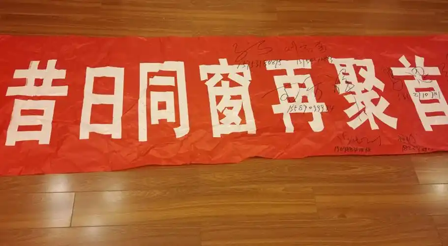 同学们在同桌王方祥为聚会题词制作的条幅上签名留念.