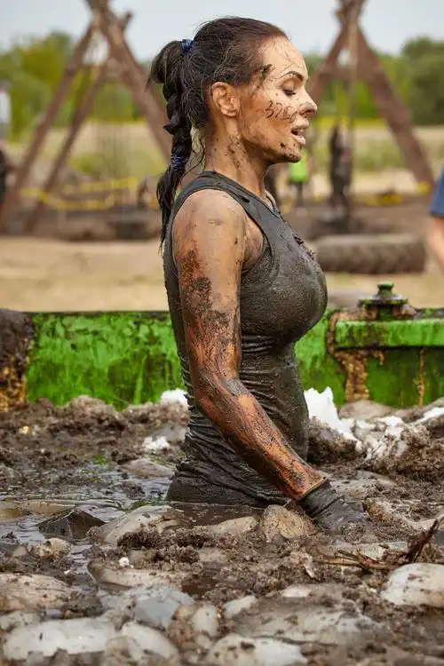 绿色户外背景下的爬出泥潭的美女