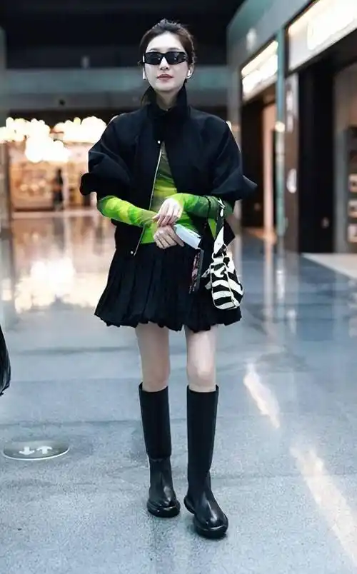 江疏影现身上海,身穿绿色t恤搭配黑色夹克,百褶裙和高筒靴,尽显时尚
