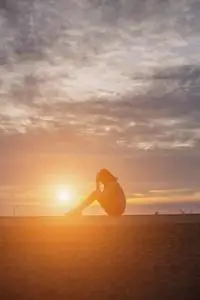 轮廓关于孤独的情绪低落的和悲哀的女人哭和热烈地拥抱她膝盖照片