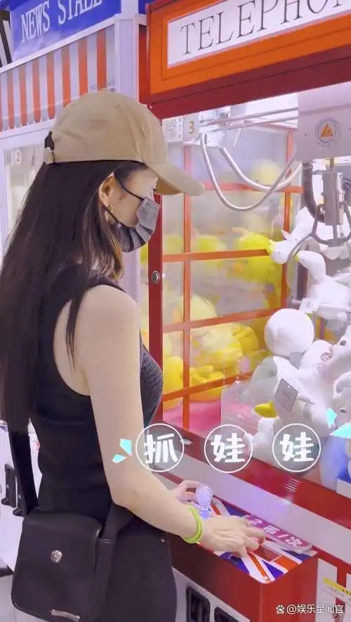 杨幂夹娃娃秀童心,穿黑色连衣裙身材凹凸有致,与助理互动如初恋