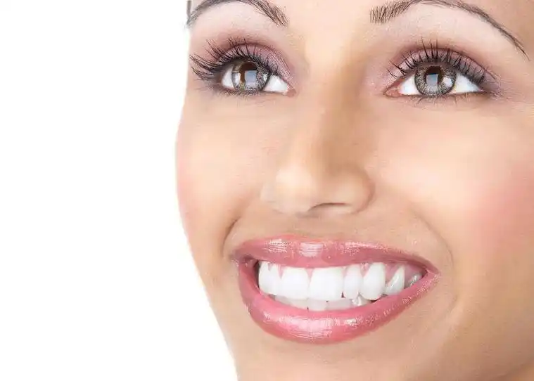 白色背景下张开嘴巴露出牙齿微笑的美女