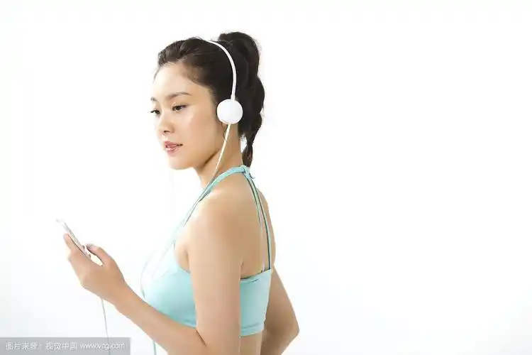 侧面的女人穿着运动服听音乐戴着耳机与智能手机