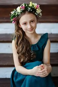 漂亮可爱的小女孩,长发,绿色连衣裙,头戴鲜花花环,微笑着看着镜头照片