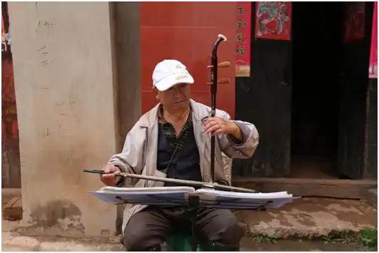 晋宁县上蒜镇海埂村村民杨玉衡拉二胡清晨,泥泞的乡间小路上传来"啪嗒