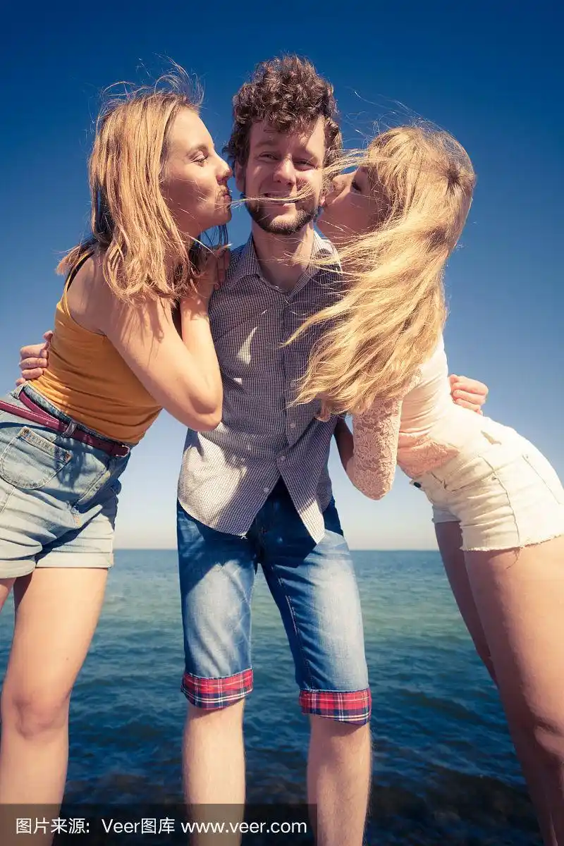 两个女孩在户外亲吻一个男孩