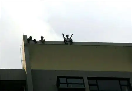 3名男子坐在26层建筑楼顶边缘,几只脚悬空在外晃荡.