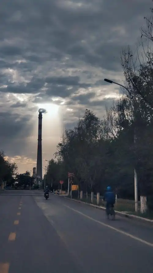 清晨上班路上一缕阳光透过厚厚的云层落在单位烟囱上