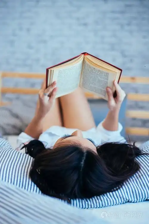 在上午在家看书在她的床上的女人