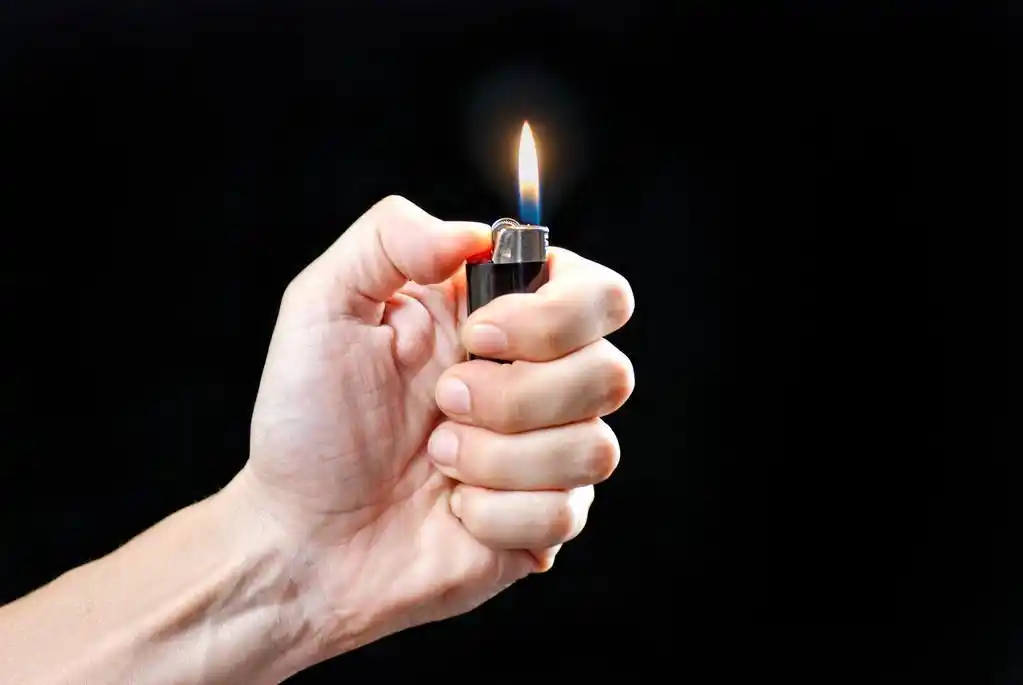 手举行点燃打火机,一个男人手拿着一个点燃的打火机的特写镜头.