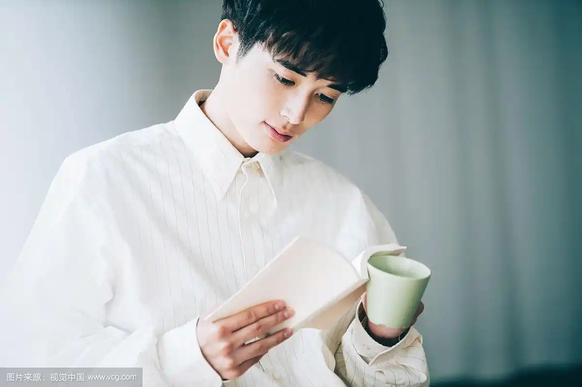 一个穿白衬衫的男人在窗边看书