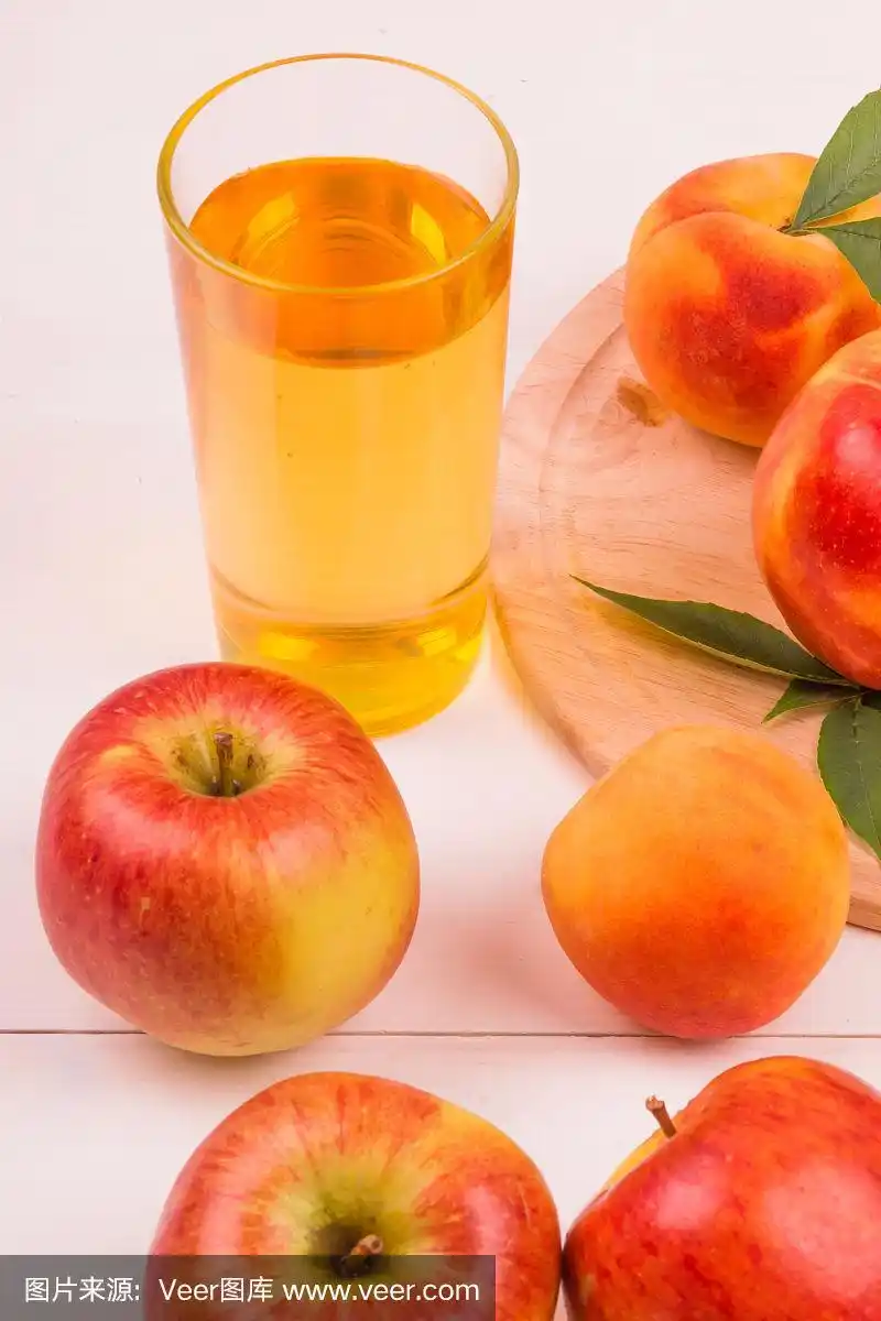 一杯苹果汁,桃子和成熟的新鲜水果在一个明亮的背景