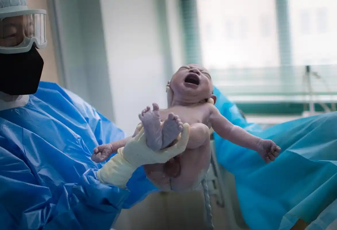 3月1日,在武汉市妇幼保健院,助产士将新出生的宝宝抱给产妇看.