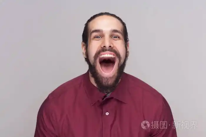 滑稽惊奇的人与黑头发和胡子在红色衬衣站立和看在照相机与大张开的嘴