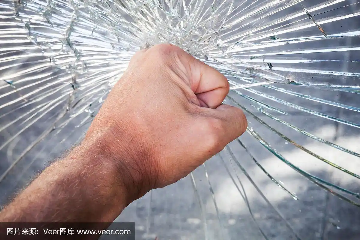 有力的男性拳头与破碎的玻璃