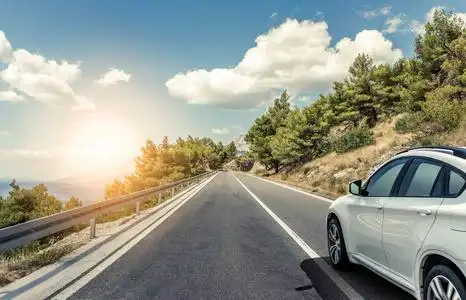 一辆白色汽车沿着高速公路在阳光下行驶照片