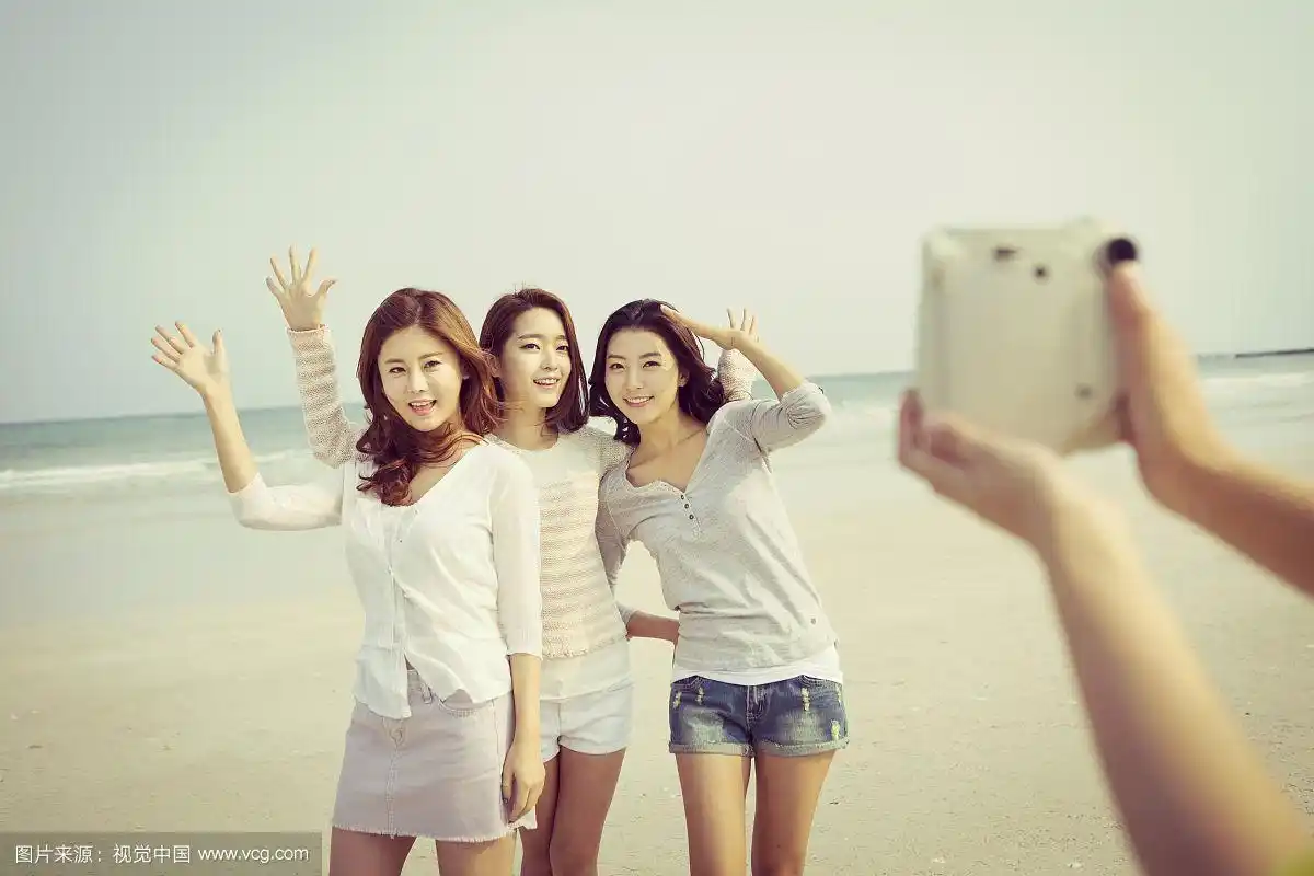 三个女人在海滩上拍照的照片